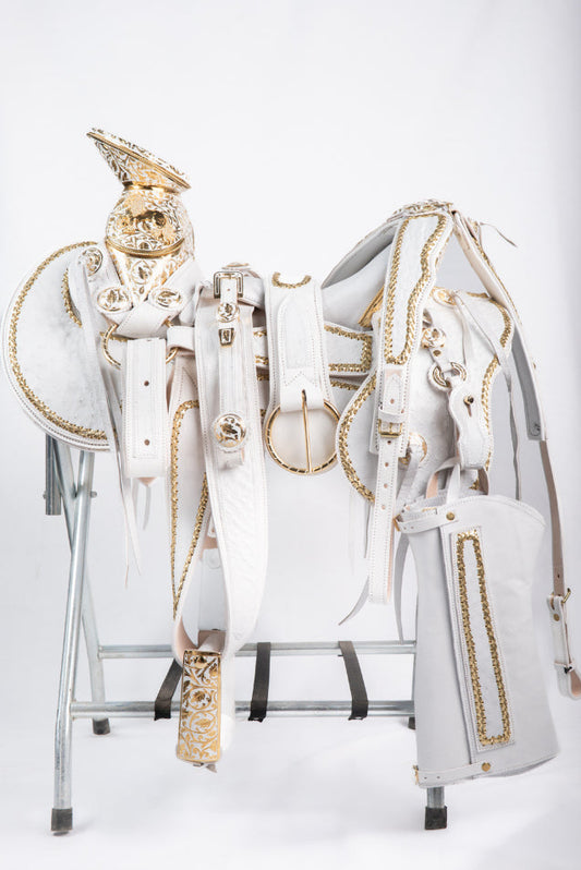 MONTURA COLA DE PATO CON CANTINA DE PIEL DE AVESTRUZ BLANCA GUARDAS TRENZADAS DORADAS FUSTE Y HERRAJE DE ACERO MONEL FONDO BLANCO CON PEDRERIA DE ZIRCONIA